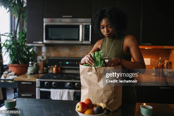 young woman comes home from grocery shopping - unpacking stock pictures, royalty-free photos & images