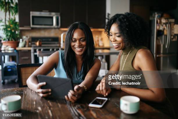 jonge vrouwen thuis, kijken spul op tablet samen - nosotroscollection stockfoto's en -beelden