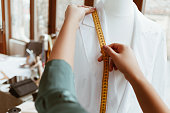 Design studio. Shirt and measurement tape in woman hands