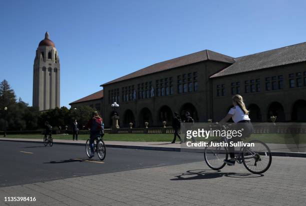 Cyclists ride by Hoover Tower on the Stanford University campus on March 12, 2019 in Stanford, California. More than 40 people, including actresses...