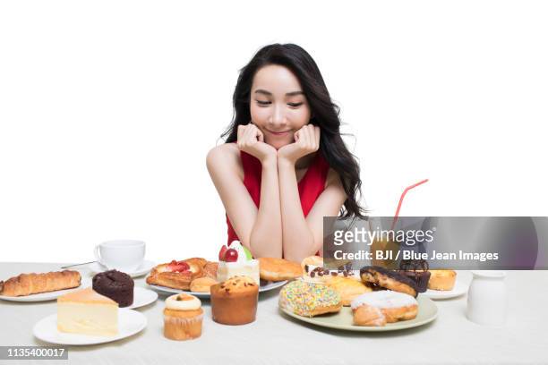 fashionable young woman eating dessert - blue donut white background imagens e fotografias de stock