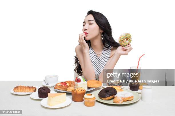 fashionable young woman eating dessert - blue donut white background imagens e fotografias de stock