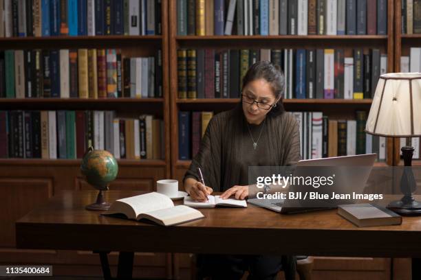 elegant mature woman using laptop in study - authors night ストックフォトと画像