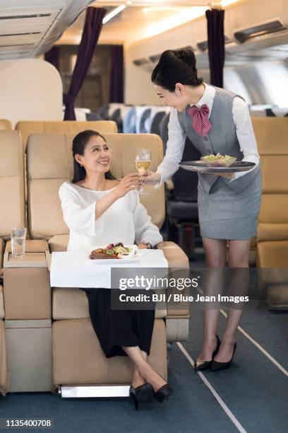 airline stewardess serving food to passenger - first class airline stock pictures, royalty-free photos & images