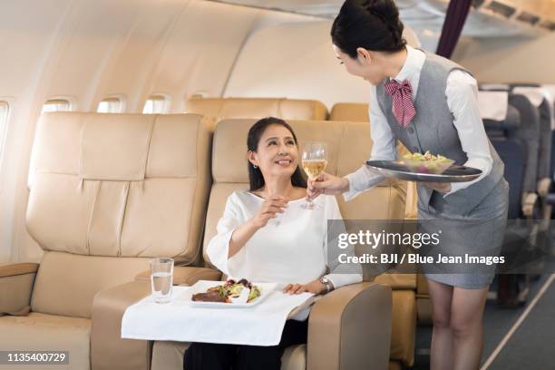 airline stewardess serving food to passenger - first class flight stock pictures, royalty-free photos & images