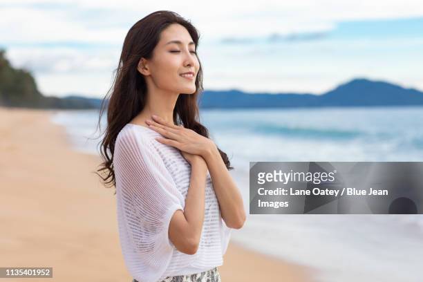 happy young woman on beach - main sur la poitrine photos et images de collection
