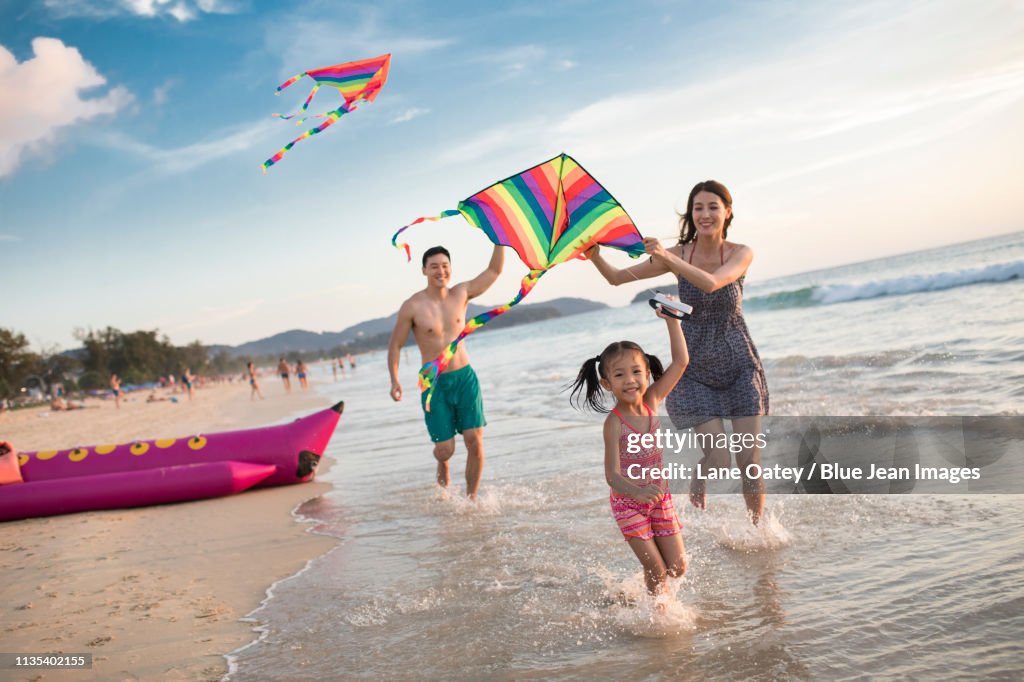Happy young family flying a kite on beach