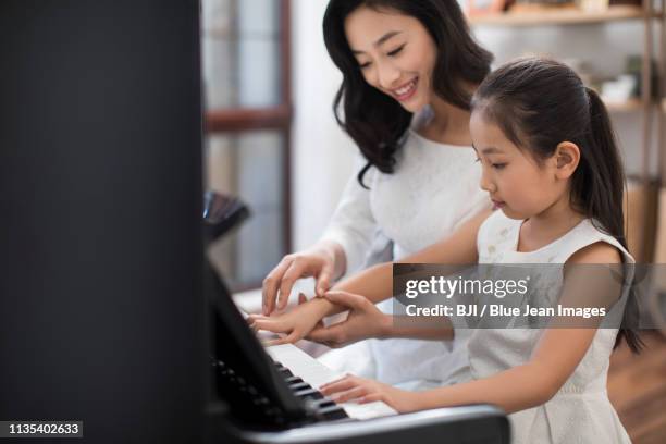 mother teaching daughter to play the piano - keyboard musical instrument child stock pictures, royalty-free photos & images