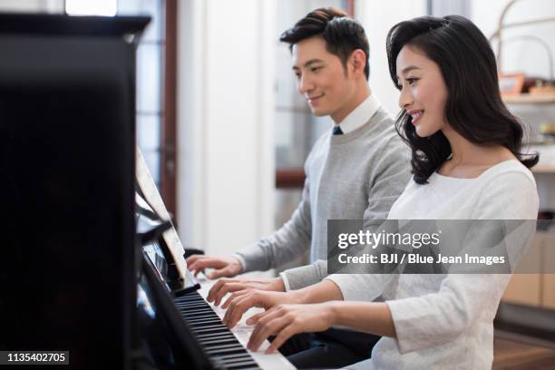 noble young couple playing the piano together - fabolous musician stockfoto's en -beelden