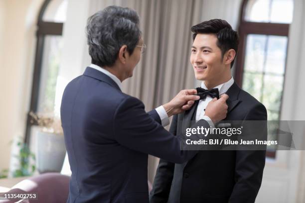 senior father adjusting bow tie for his son - adjusting blue tie stock-fotos und bilder