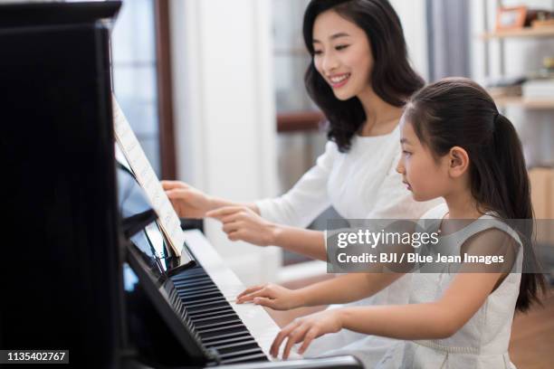 mother teaching daughter to play the piano - fabolous musician bildbanksfoton och bilder