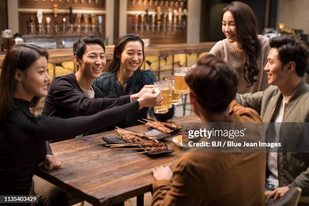 happy friends toasting and talking in bar - ビールジョッキ ストックフォトと画像