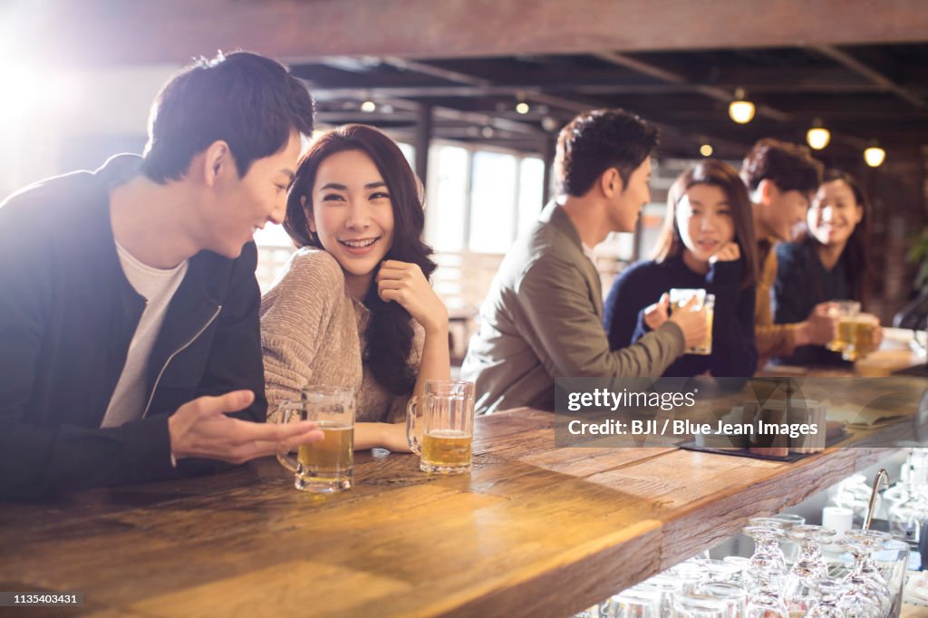 Happy friends drinking beer and talking in bar