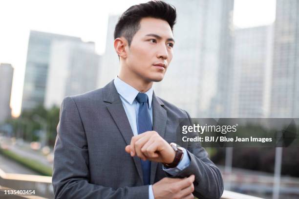young businessman adjusting cuff - adjusting blue tie stock-fotos und bilder