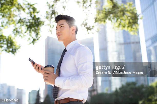 confident young businessman using smart phone - asian businessman phone stockfoto's en -beelden