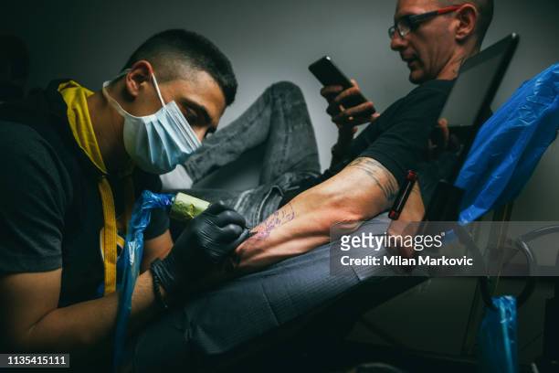 tatuaje maestro haciendo tatuaje - arm tattoos for black men fotografías e imágenes de stock
