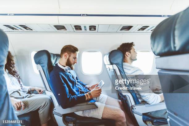 hombre usando tableta digital durante su viaje en avión - passengers 2016 film fotografías e imágenes de stock