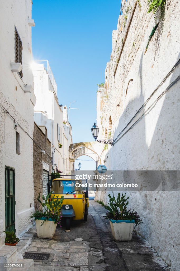 Traditional alley with three-wheeler in the city of Ostuni, Puglia, Italy