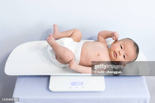 weging baby op schaal - weegschaal weeginstrument stockfoto's en -beelden