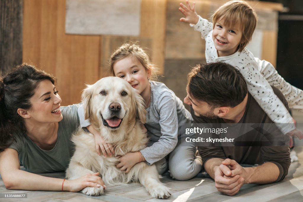 Happy family relaxing with their retriever at home.