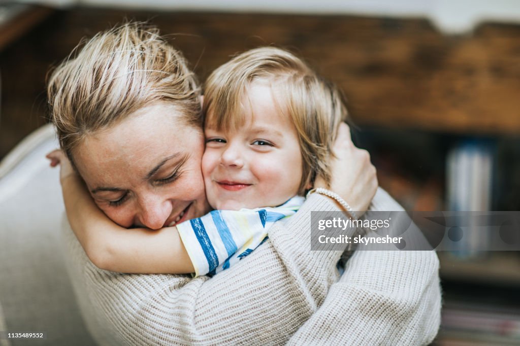 Cariñosa Madre e hijo abrazando en casa.