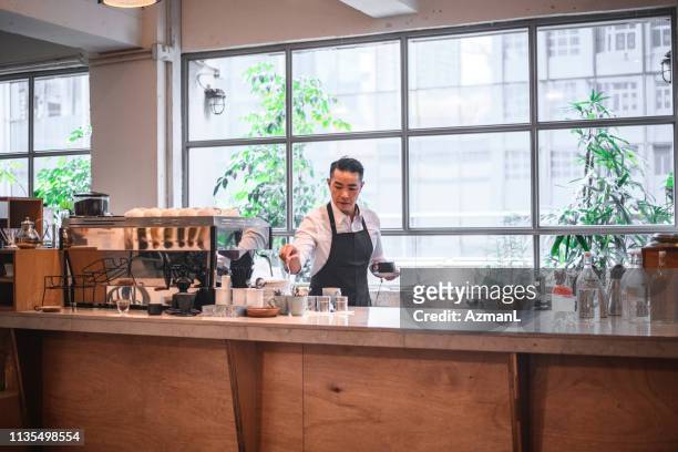 Mature barista holding coffee cup at counter