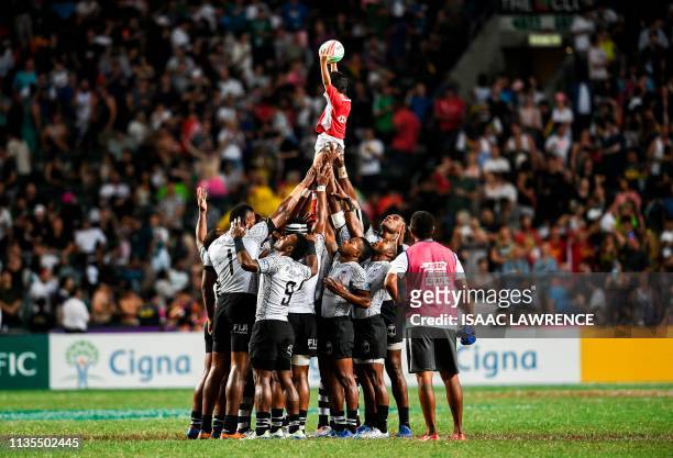 Fiji lift a ball boy in the air before the start of the Cup final against France on the Third day at the Hong Kong Sevens rugby tournament on April...