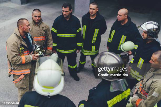 team von feuerwehrleuten hört anweisungen - rescue worker stock-fotos und bilder