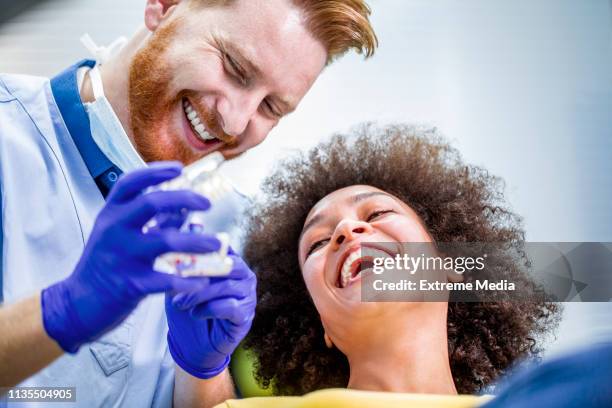 een tandarts demonstreren hoe goed tanden te wassen om zijn patiënt met behulp van een tandenborstel en een set van anatomische tanden model - drill bit stockfoto's en -beelden