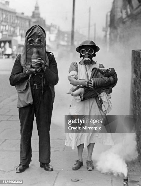 Air raid warden with nurse and baby in arms seen demonstrating the new gas helmet during an air raid gas exercise on Merseyside 24th July 1941.