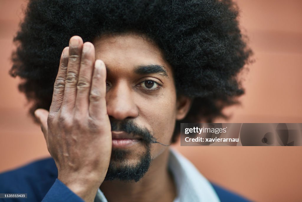 Portrait of executive covering half face with hand