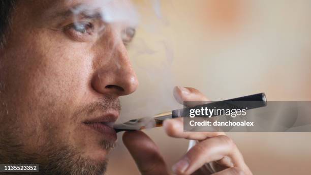 young man using electronic cigarette - electronic vapor stock pictures, royalty-free photos & images