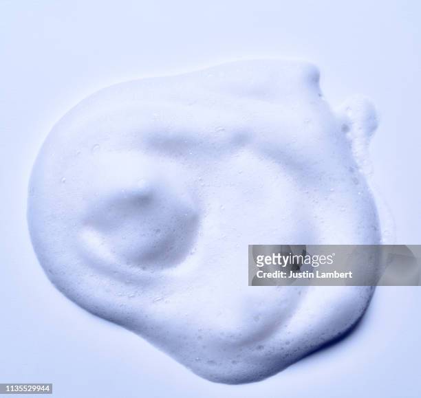 droplets of foam on white background - froth stock-fotos und bilder