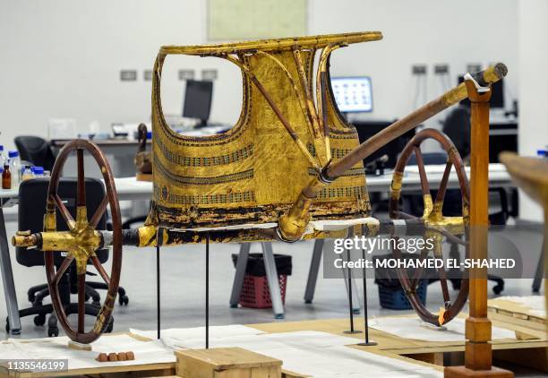 This picture taken on April 7, 2019 shows a view of the gilded chariot of the Tutankhamun collection currently undergoing work at the restoration lab...