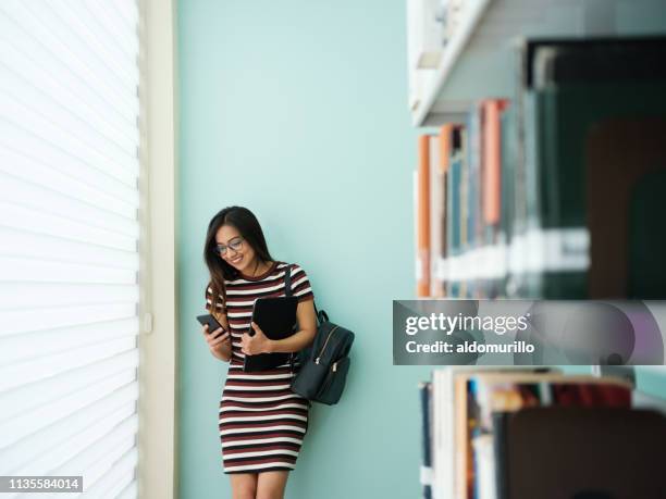 glimlachende student sms - college student holding books stockfoto's en -beelden