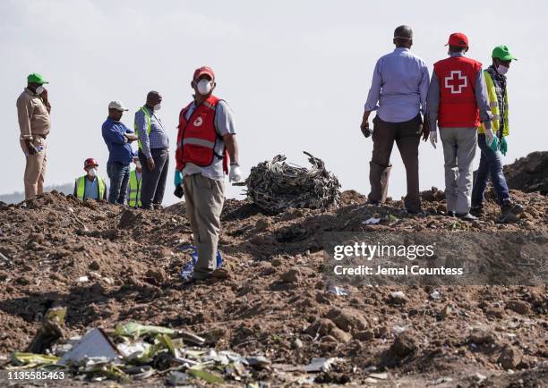 Investigators and recovery workers inspect a second engine after it is recovered from a crater at the scene of the Ethiopian Airlines Flight 302...