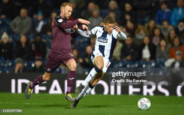 Striker Dwight Gayle is challenged by Swansea captain Mike van der Hoorn during the Sky Bet Championship match between West Bromwich Albion and...