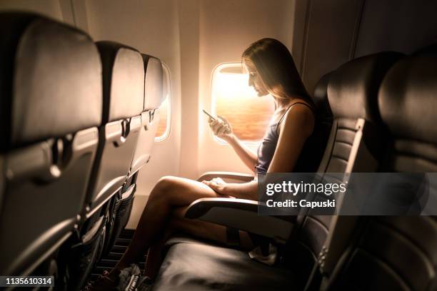 frau mit smartphone in flugzeug-sitz - airplane phone stock-fotos und bilder