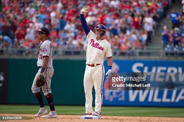 Rhys Hoskins of the Philadelphia Phillies reacts in front of Ehire Adrianza of the Minnesota Twins after hitting a double in the bottom of the eighth...