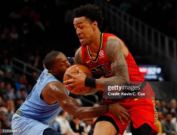 John Collins of the Atlanta Hawks drives against CJ Miles of the Memphis Grizzlies in the second half at State Farm Arena on March 13, 2019 in...