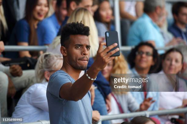 man die een selfie op een voetbalwedstrijd - voetbalcompetitie sportevenement stockfoto's en -beelden