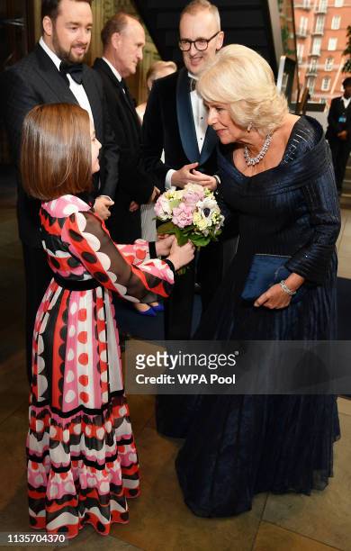 Camilla, Duchess of Cornwall is given flowers by Harriet Turnbull as she arrives to attend the Olivier Awards at the Royal Albert Hall on April 7,...