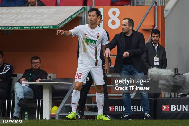 Dong-Won Ji of FC Augsburg speaks with Head coach Manuel Baum of FC Augsburg during the Bundesliga match between FC Augsburg and TSG Hoffenheim at...