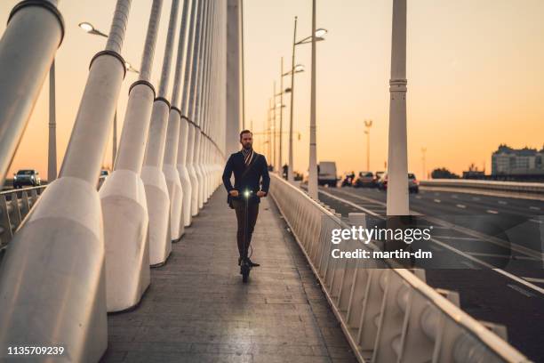 businessman riding scooter at evening - leading people across a bridge stock pictures, royalty-free photos & images