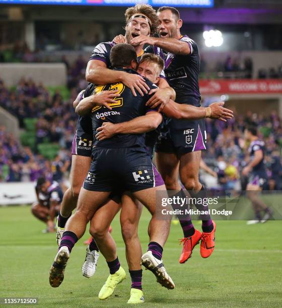 Kenneath Bromwich of the Storm is hugged by Cameron Munster, Christian Welch and Cameron Smith of the Storm after scoring a try during the round one...