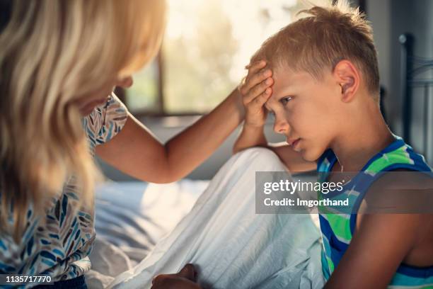 mother taking care of little boy with a head ache - fever stock pictures, royalty-free photos & images