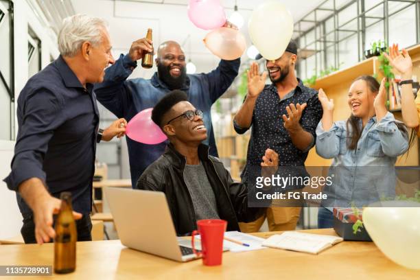 ビジネスの同僚は、現代のスタートアップ企業でサプライズ誕生日パーティーに - work anniversary ストック�フォトと画像