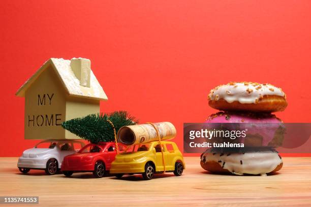 close-up of christmas tree with toy cars and donuts on wooden table against red background - sweet little models stock pictures, royalty-free photos & images
