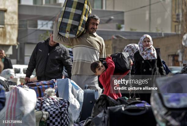 April 2019, Lebanon, Beirut: Syrian refugees carry their belongings as they prepare to board a bus that will take them back to Syria. Hundreds of...