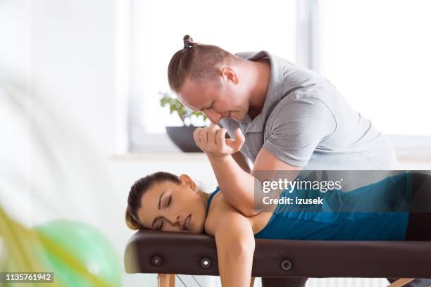 physiotherapist massaging young woman - chiropractic stock pictures, royalty-free photos & images